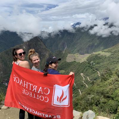 Carthage students pose with a Carthage flag while visiting Peru during January Term.